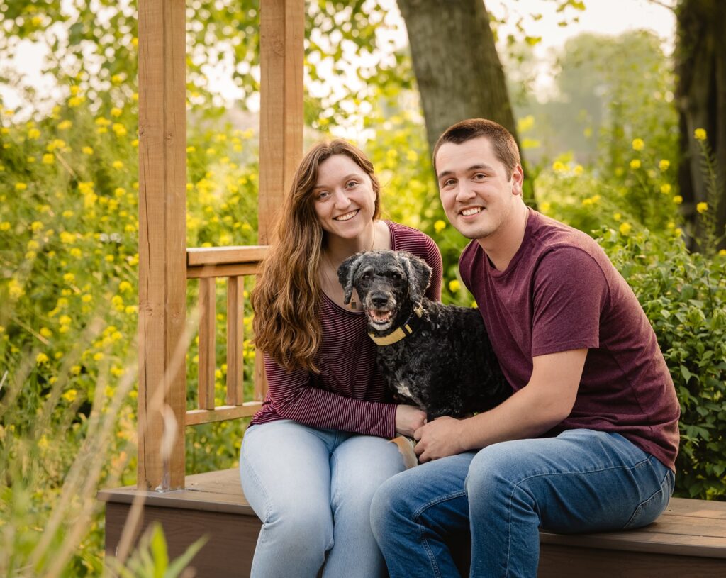 man and woman sitting with dog between them during a senior dog photography session 